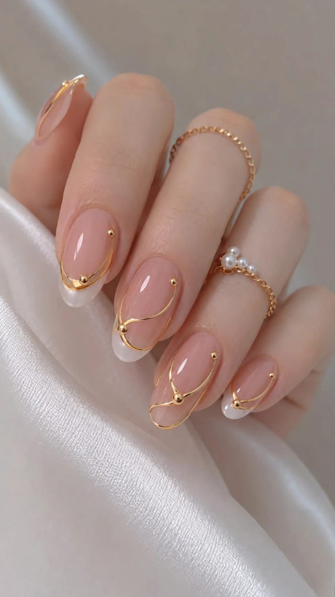 Nude almond gel manicure with gold wire line art and pearl accents